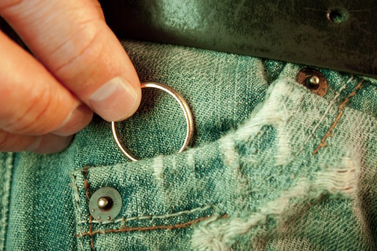 A man puts his wedding ring in his pocket