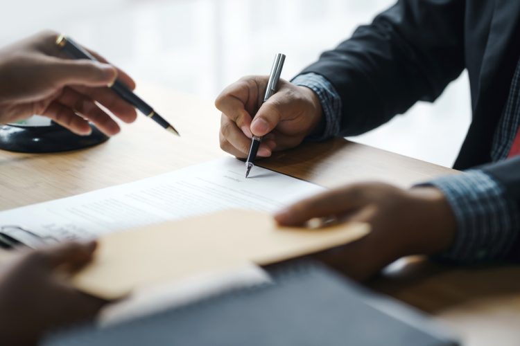 Two people signing a bankruptcy deal document