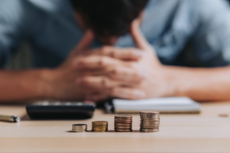 A man with his head in his hands and coins in front of him