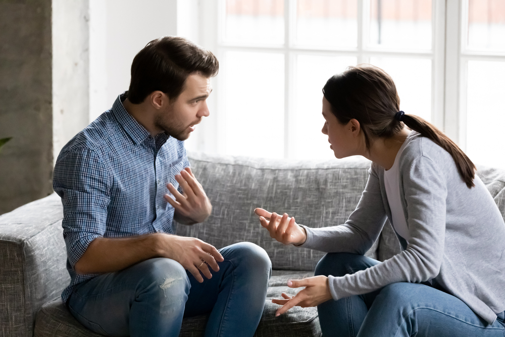 A man and woman arguing on a couch