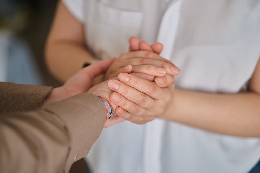 Close up of two people holding hands.