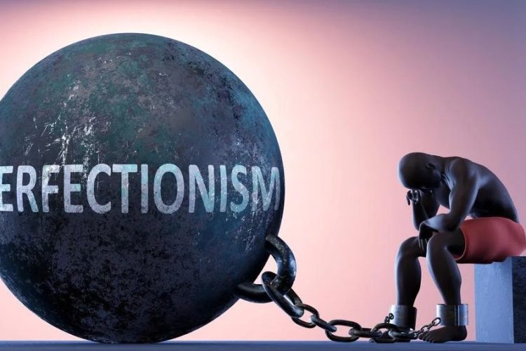 A man shackled to a perfectionism weight