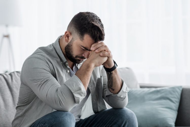 A man sitting on the couch with his head in his hands